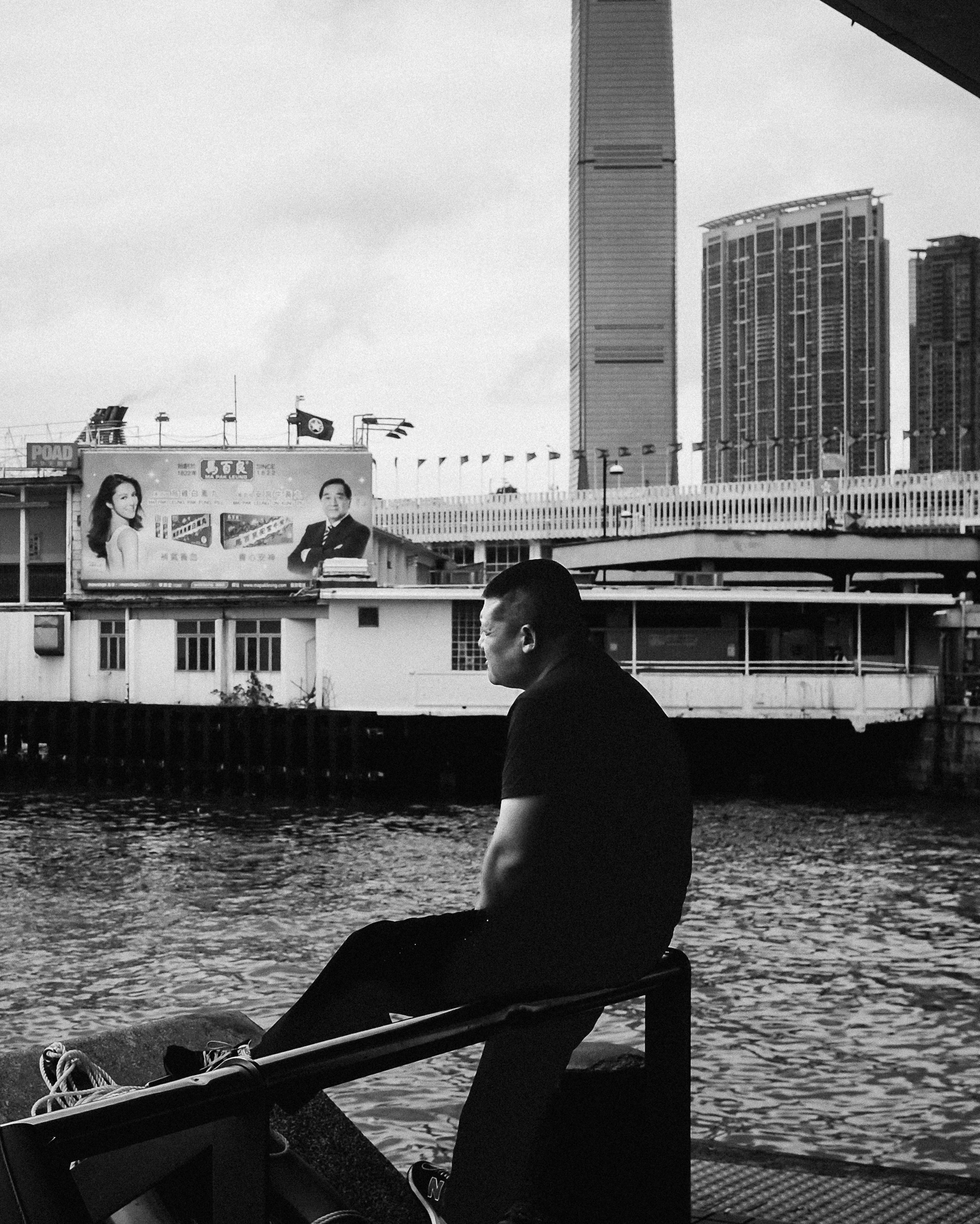 A man seated alone beside the Hong Kong waterfront