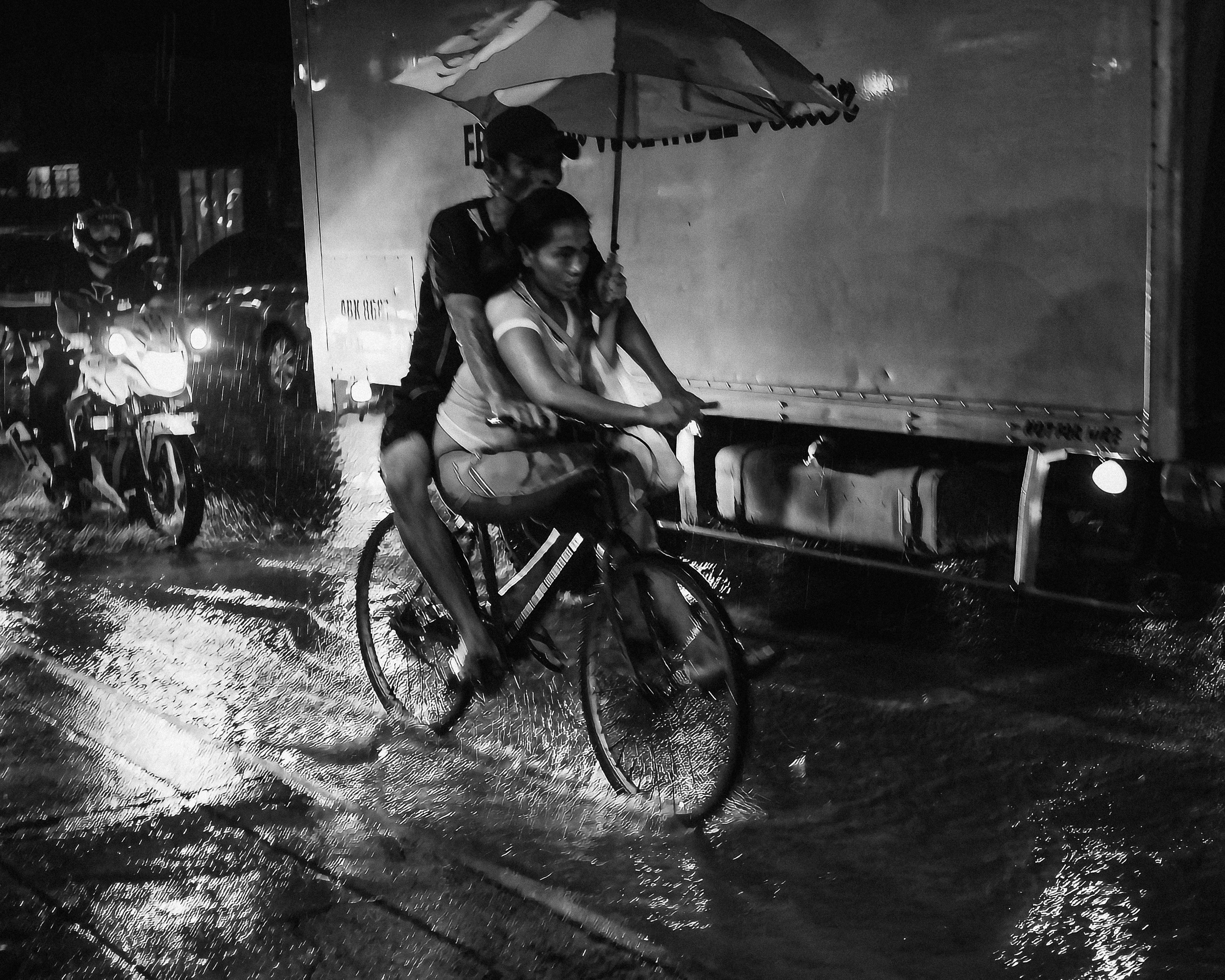 A cyclist passing through a rain-darkened street