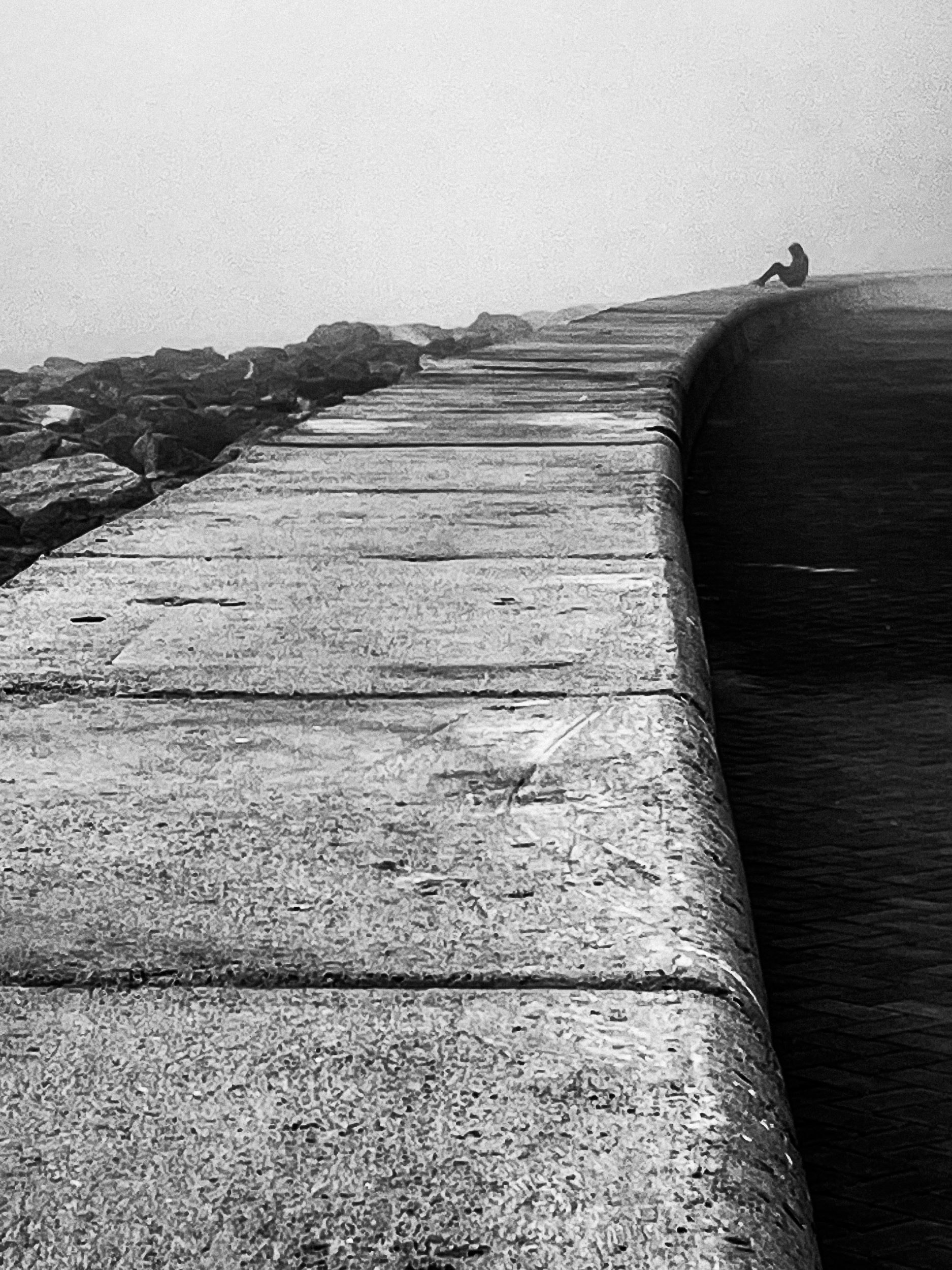 A tiny figure at the end of a sweeping seawall