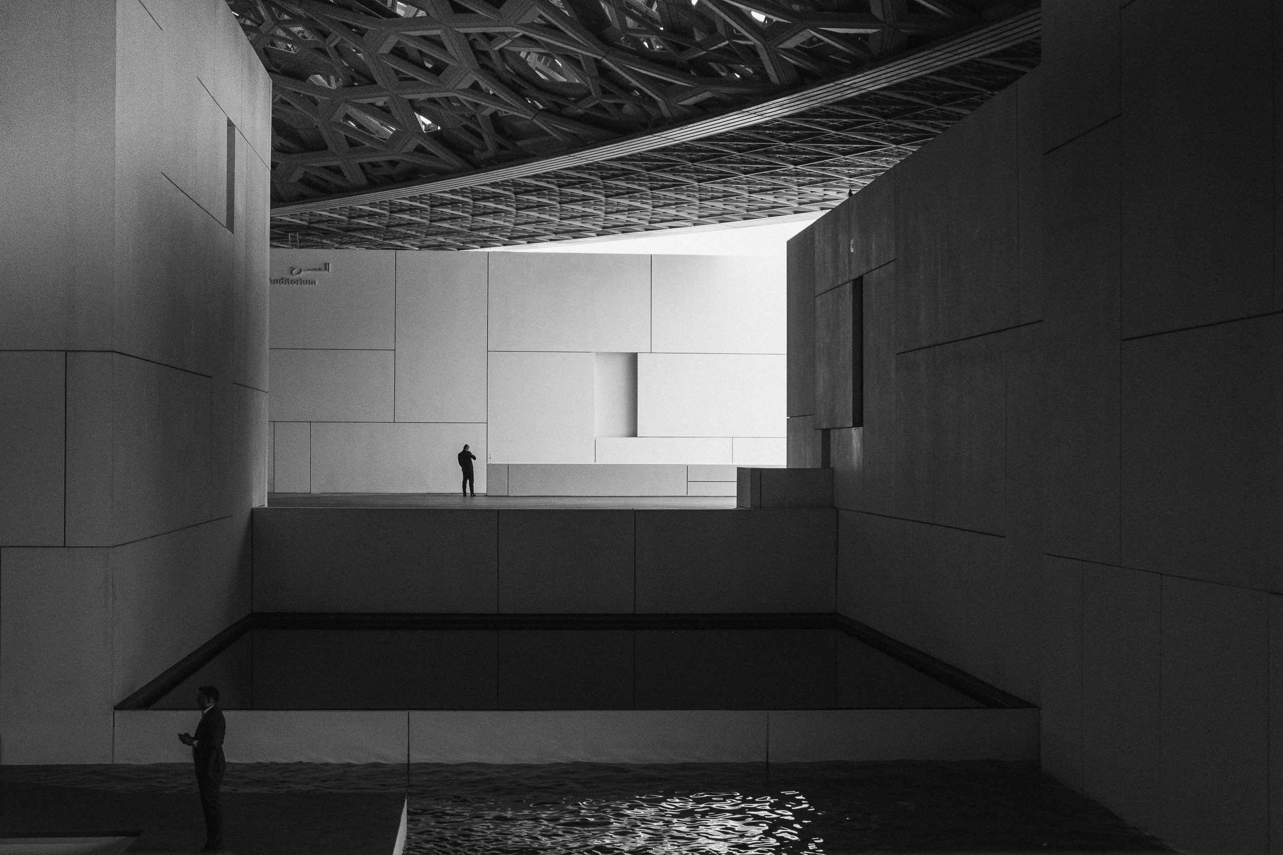 A lone figure framed by monumental geometric architecture