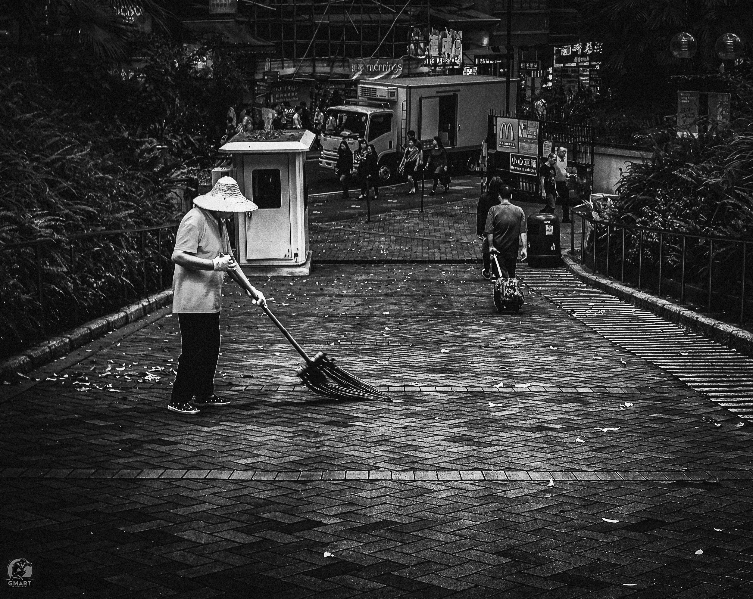 A lone street cleaner working on wet paving