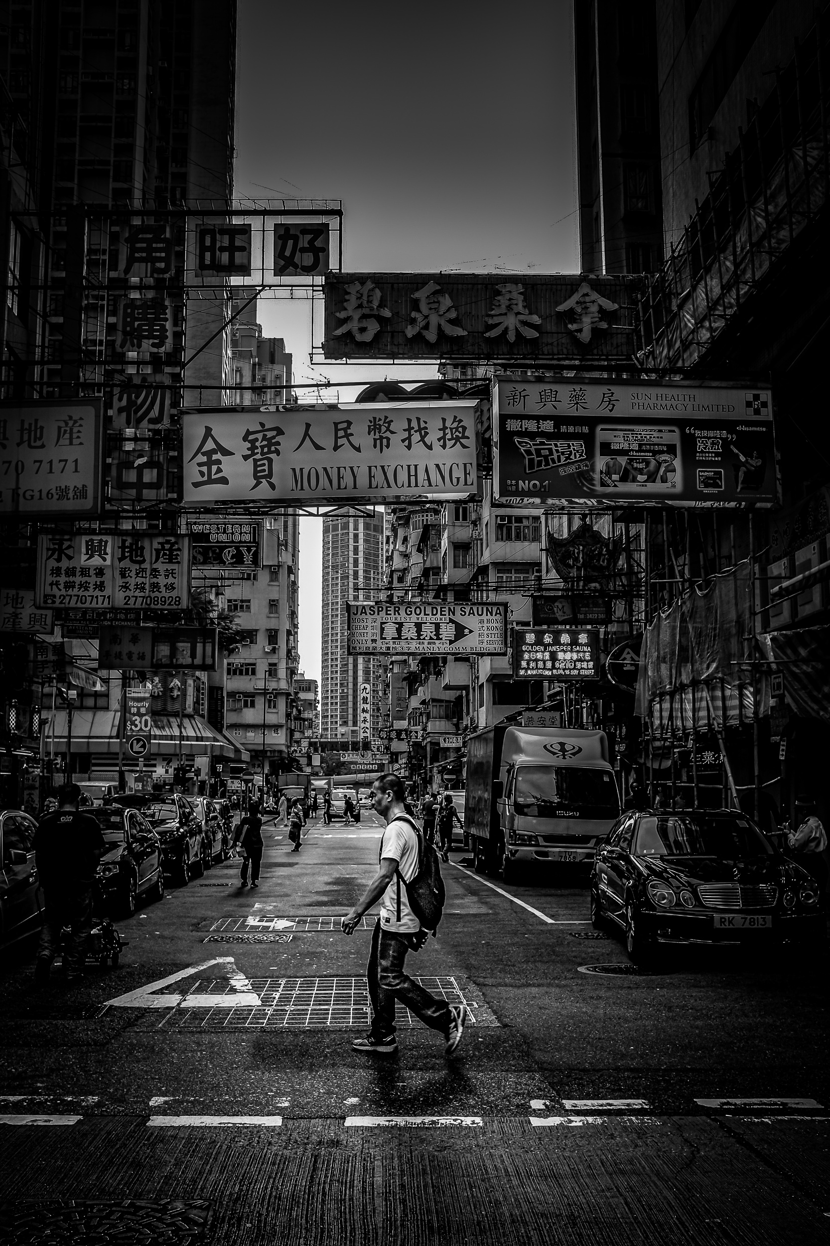 A lone pedestrian crossing beneath towering city signs