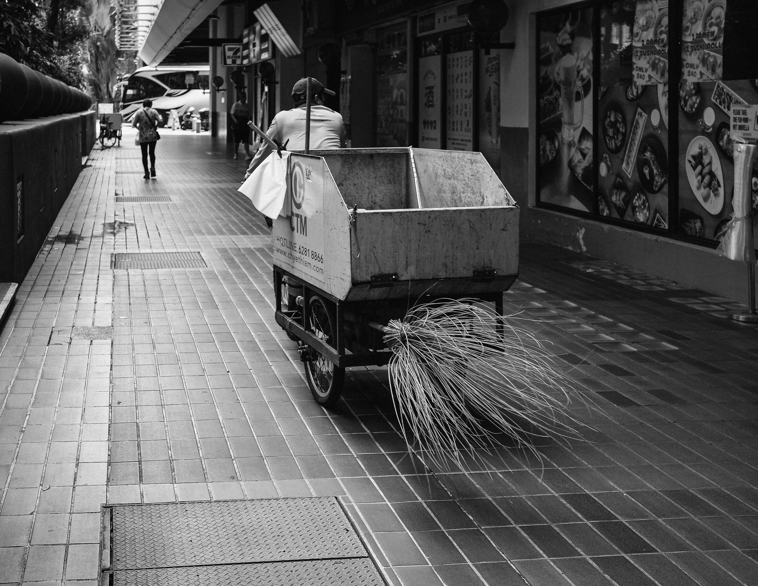 A worker pushing a large cart along a city pavement