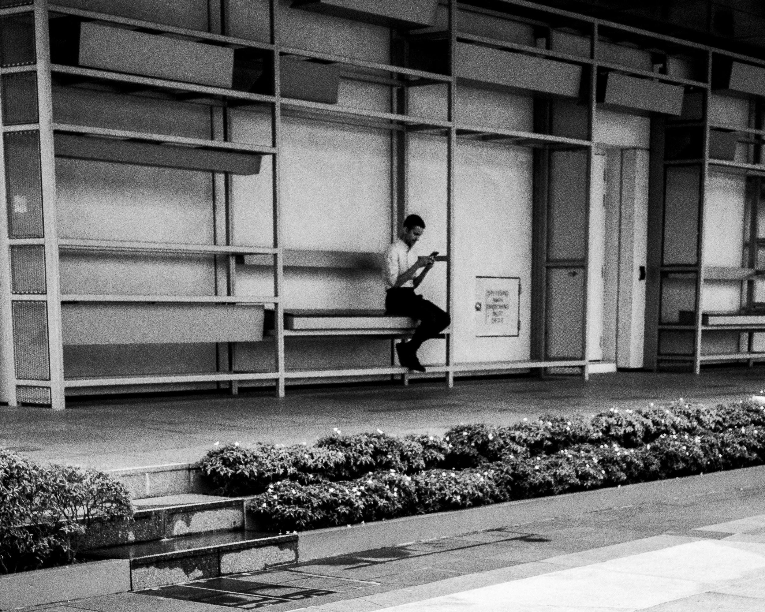 A person seated alone against a modern building