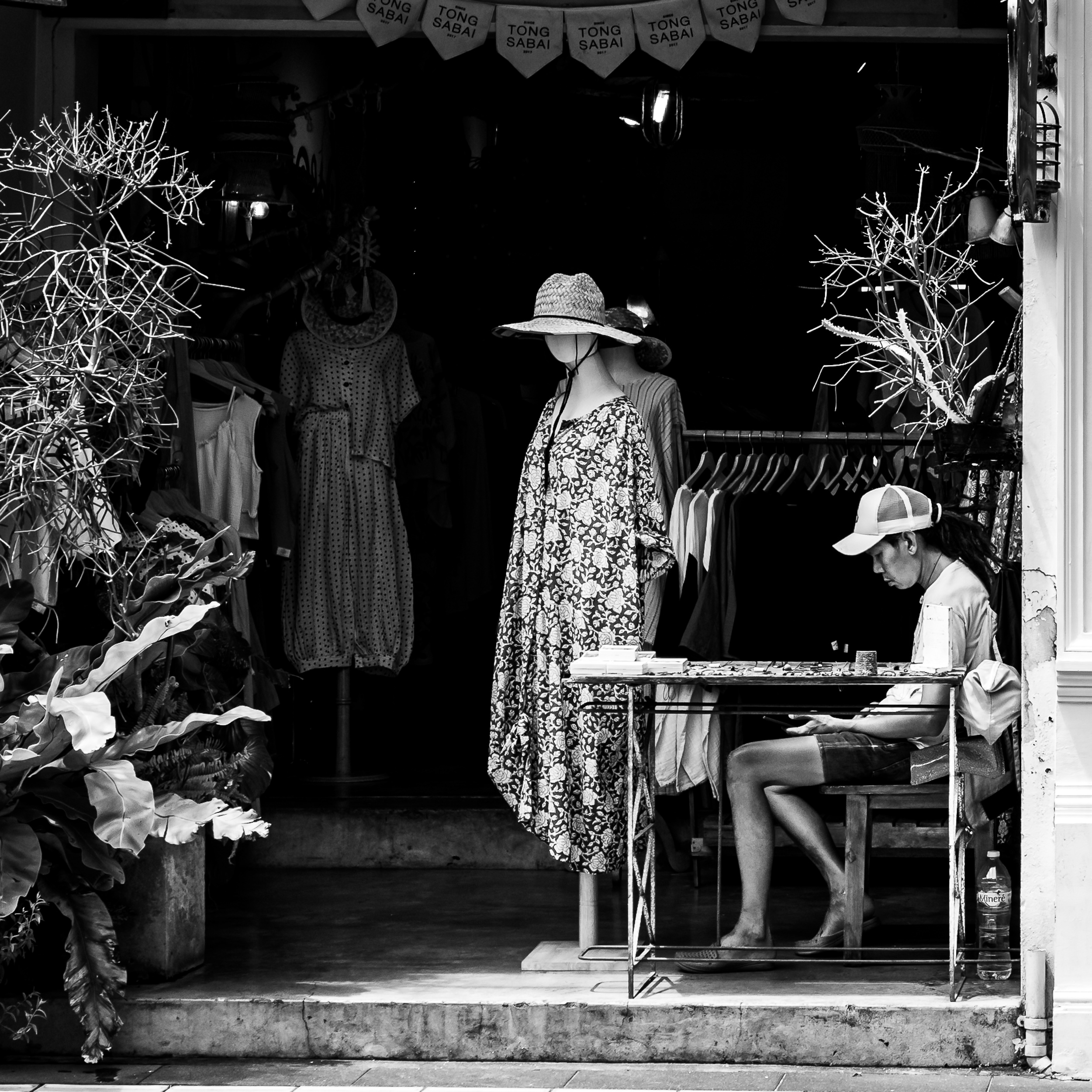 A shop worker seated among mannequins and patterned clothing