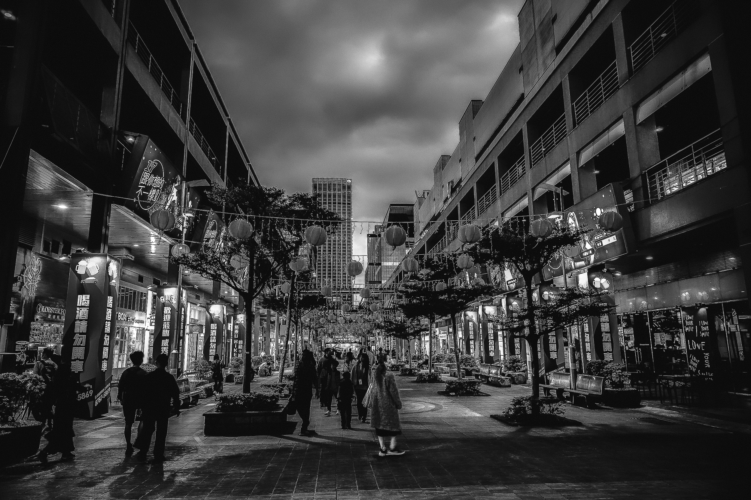 Pedestrians moving through a luminous city street at night